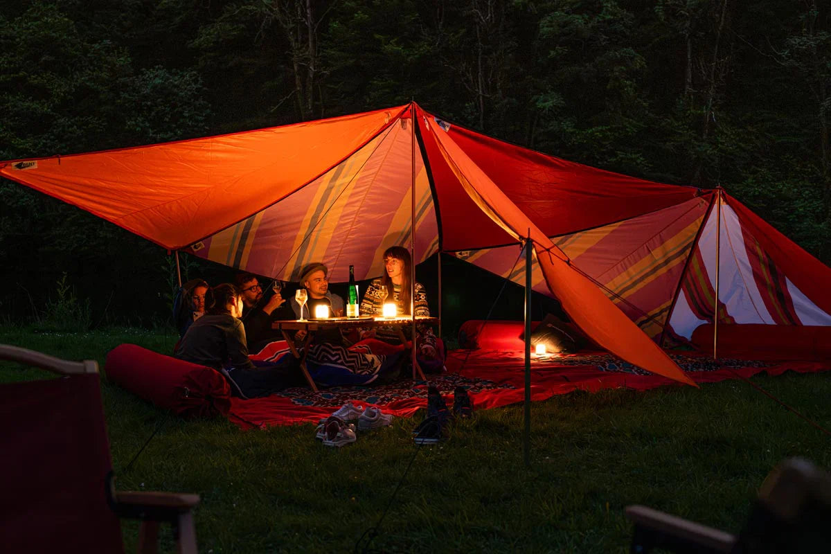 Junge Personen geniessen die Abendstimmung unter Bent Sonnensegel und auf Bent Teppich